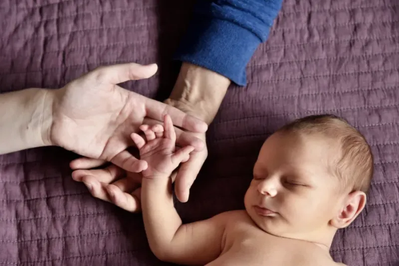 Babyhandje en de handen van zijn ouders