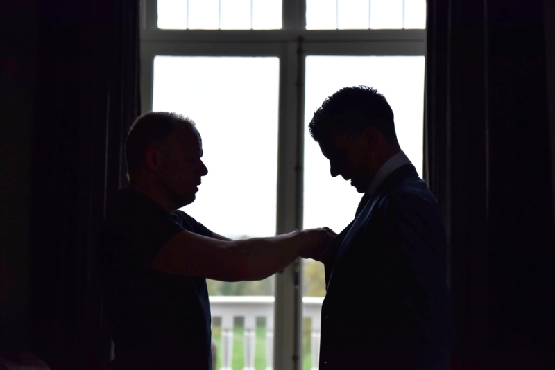 De beste vriend van de bruidegom helpt met de stropdas