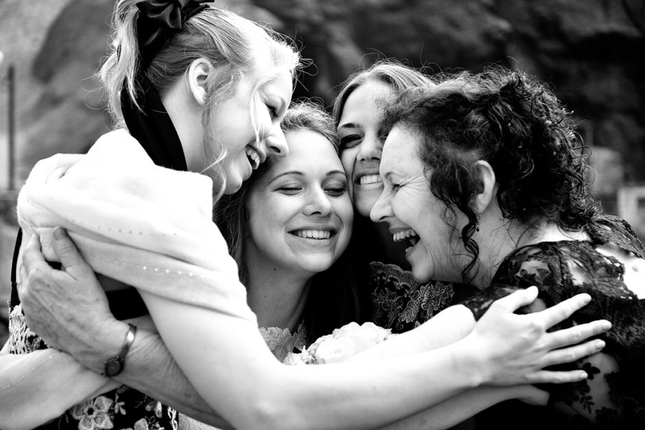 Liefdevolle bruidsfotografie bij een huwelijk in Zuid-Amerika, zussen en moeder van de bruid knuffelen de bruid.
