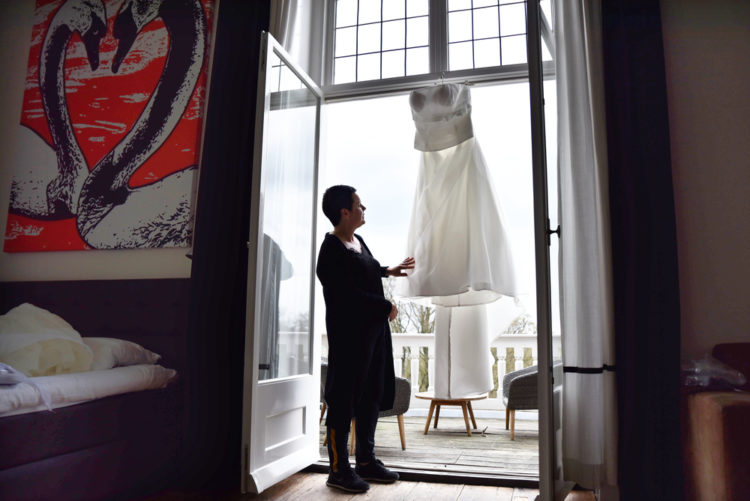 Bruid staat bij haar jurk in de bruidssuite van landgoed Rhederoord.