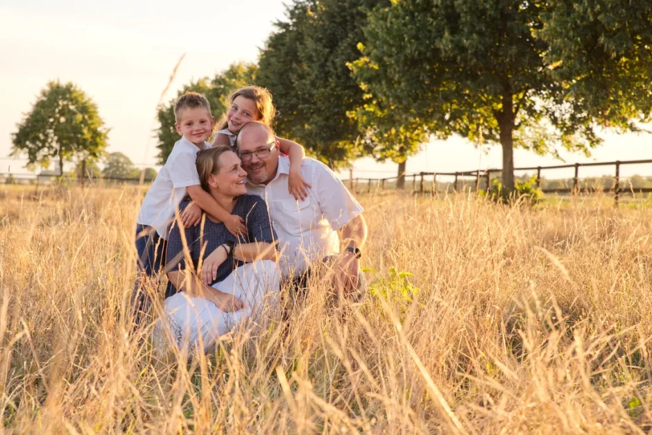Fotoshoot van een gezin. Ouders met kinderen in een weide met hoog goud gras. In Limburg en omgeving.