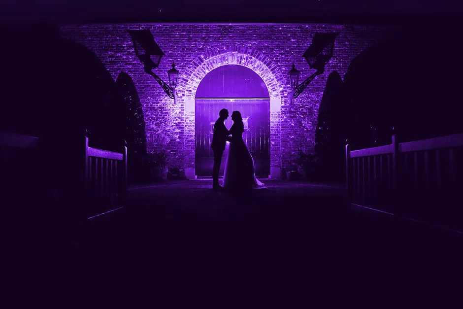 Bijzondere trouwfoto, een silhouet van het bruidspaar en paars flitslicht maken dit een hele bijzondere foto.