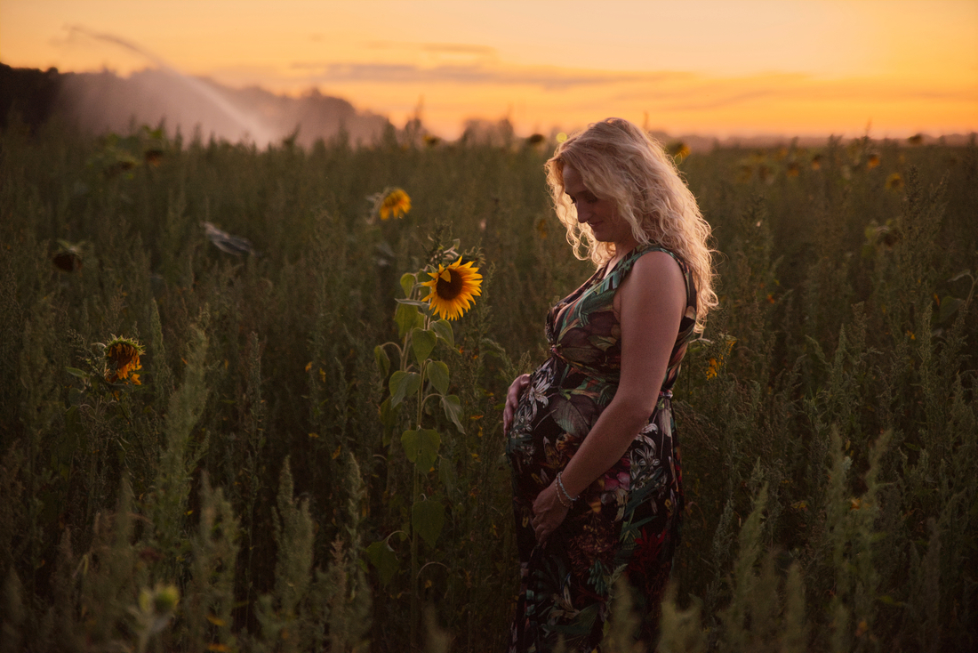 Zwangerschapsfotograaf uit Limburg fotografeert een vrouw in een veld met bloemen.