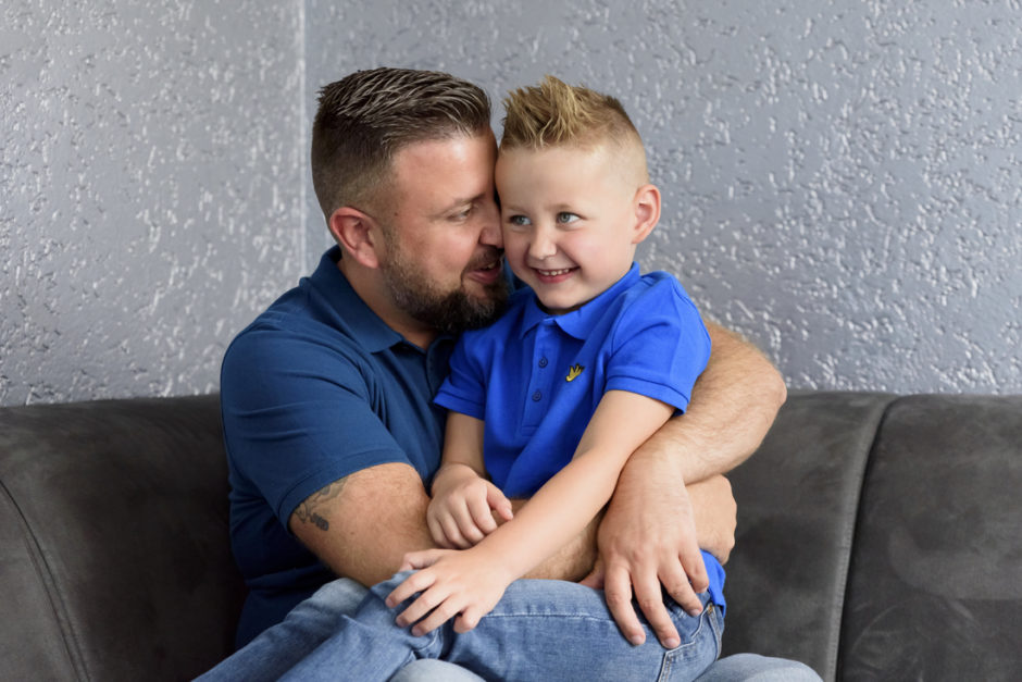 Vader en zoon tijdens een fotoshoot met kleine kinderen gewoon lekker thuis op de bank.