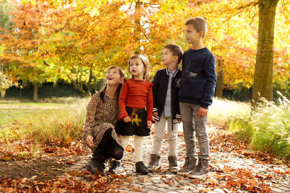 Kinderen kijken omhoog naar de herfstbladeren, fotoshoot van een gezin in Limburg.