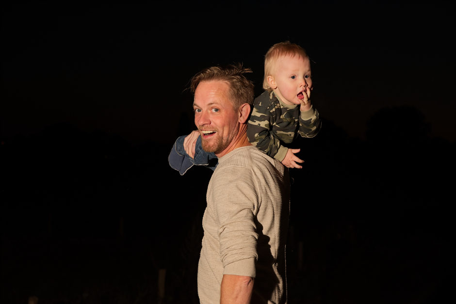 Vader met kindje tijdens een avond fotoshoot van het gezin met flitsers in midden Limburg.