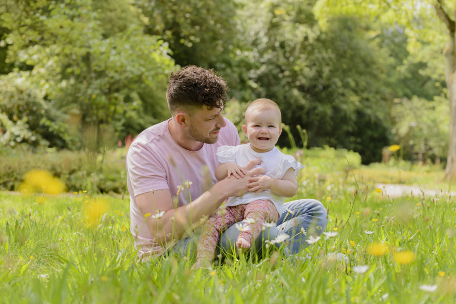 Papa en baby in het gras in het park bij kasteeltje Hattem in Roermond.