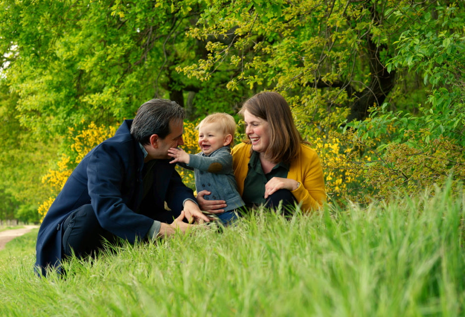 Ouders met baby in het gras om mooie foto's te laten maken van hun gezin