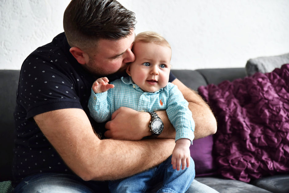 Baby en papa op de bank tijdens de fotoreportage in Limburg. Mooi kado voor babyshower.