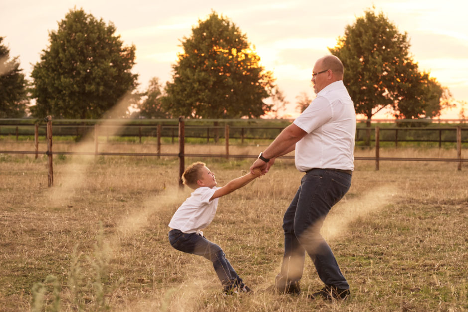 Vader en zoon spelen tijdens de avond als de zon al bijna onder is.