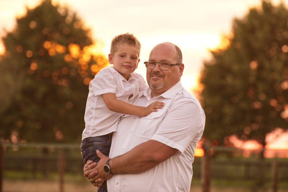 Portret vader met zoon op de arm, tijdens een familie fotoreportage in de natuur in Duitsland, tijdens het gouden uurtje bij zonsondergang.