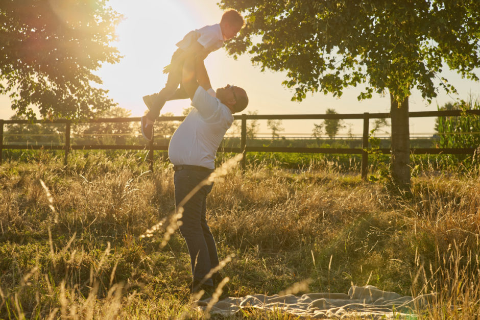 Vader gooit zoon in de lucht, tijdens een familie fotoreportage in de natuur in Duitsland, tijdens het gouden uurtje bij zonsondergang.