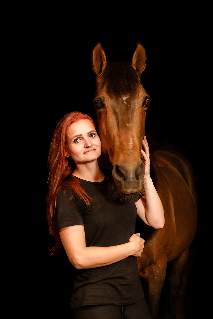 Portret van een vrouw en haar paard tijdens een paardenfotoshoot op stal met donkere achtergrond, in Limburg bij Roermond.