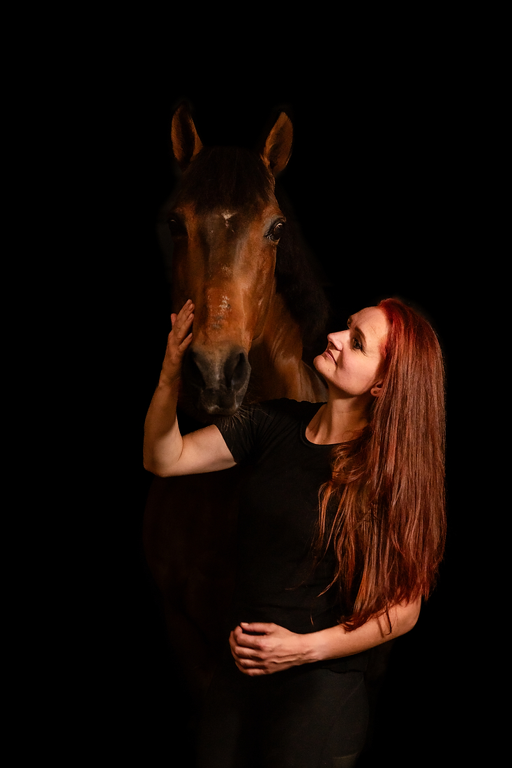 Portret van een vrouw en haar paard tijdens een paardenfotoshoot op stal met donkere achtergrond, in Limburg bij Roermond.