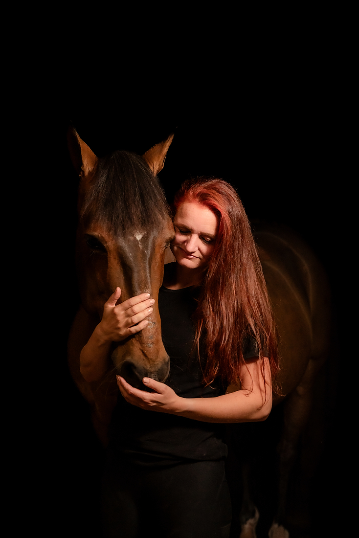Vrouw en paard tijdens een paardenfotoshoot op stal met donkere achtergrond, in Limburg bij Roermond.