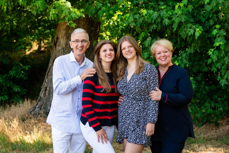 Ouders met twee dochters op een mooie dag in het bos bij het Leudal in Limburg, tijdens hun fotoshoot van de hele familie.