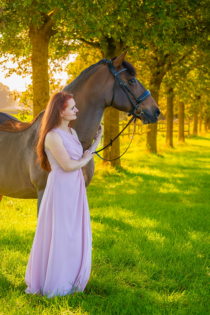 Vrouw staat langs de bomen met een paard bij een fotoshoot in Limburg. Tijdens de herfst.