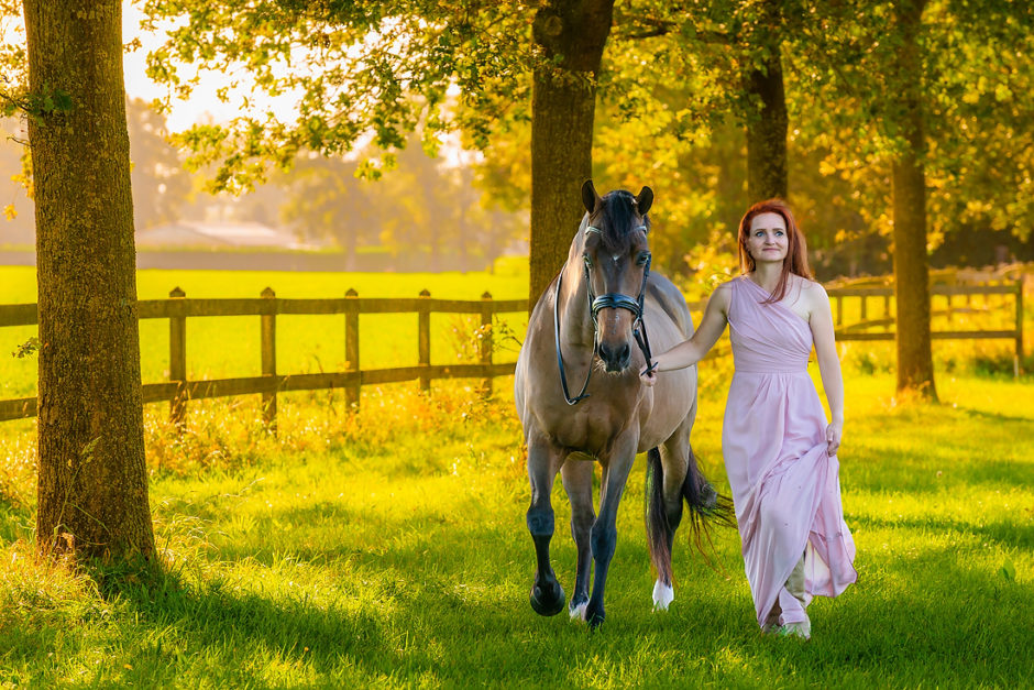 Vrouw loopt langs de bomen met haar paard tijdens de herfst.