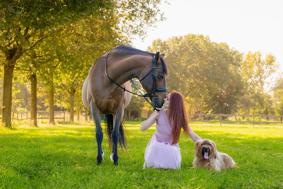 Vrouw met paard en hond in de natuur.