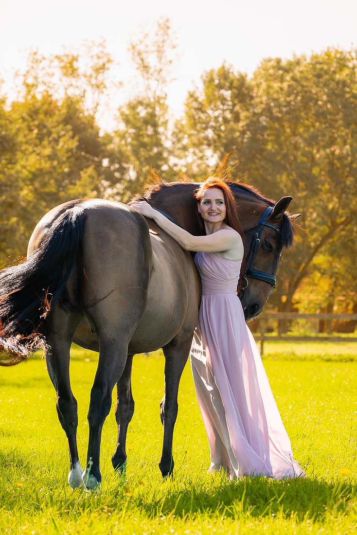 Vrouw staat in de zon met een paard bij een fotoshoot in Limburg. Met prachtige herfst kleuren.