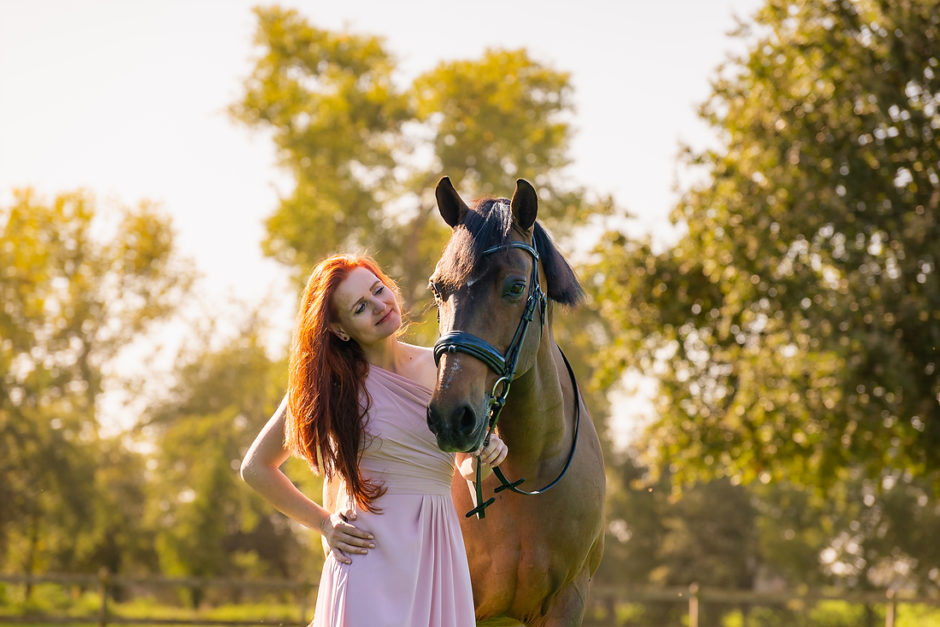 Vrouw staat in de zon met een paard in Limburg. Met prachtige herfst kleuren.