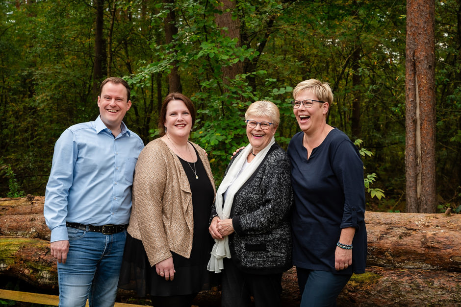 Moeder met oudere kinderen moeten lachen terwijl ze klaarstaan om op de foto te gaan, bij een familieshoot in Limburg.