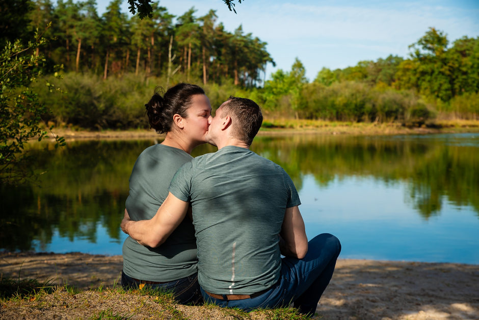 romantische foto van een koppel dat bij het water in het bos in Limburg zit, gemaakt tijdens een fotoshoot van de hele familie.