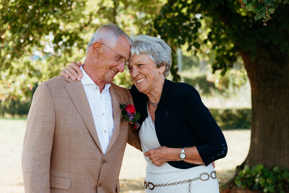 De ouders van de bruid omarmen elkaar en delen een lief momentje met de voorhoofden tegen elkaar. Door fotograaf uit Limburg, NL.