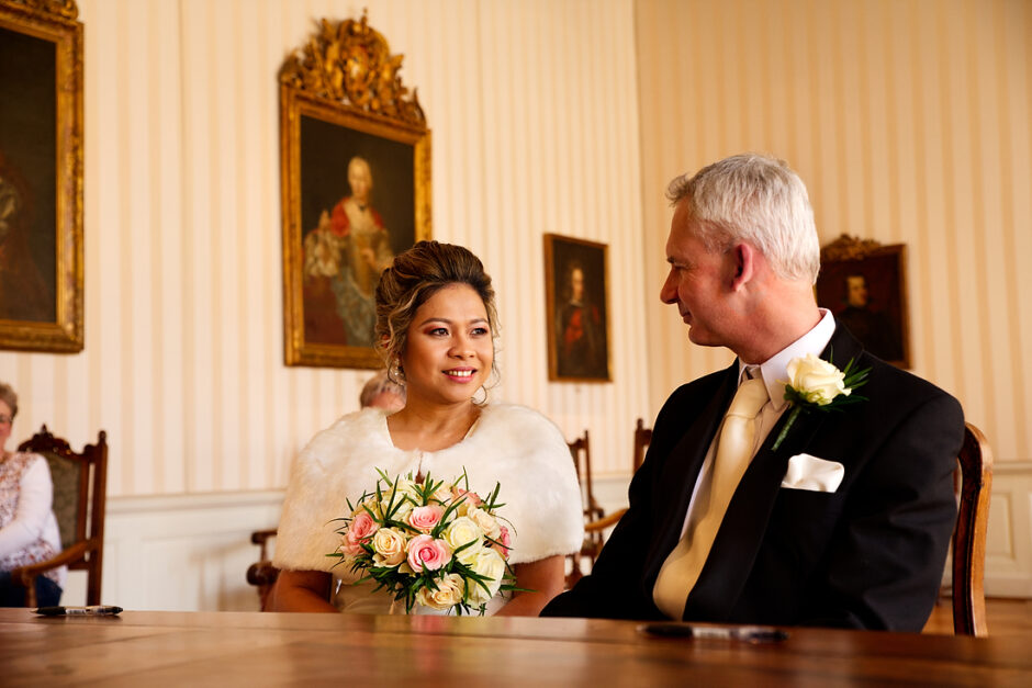  Bruidsfotografie in Roermond: liefdevolle blik tijdens partnerschap in het gemeentehuis.